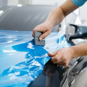 Auto wird von einer Person in Blau foliert